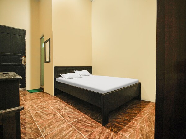 A small, neatly arranged bedroom with a single bed, a dresser, and a door.