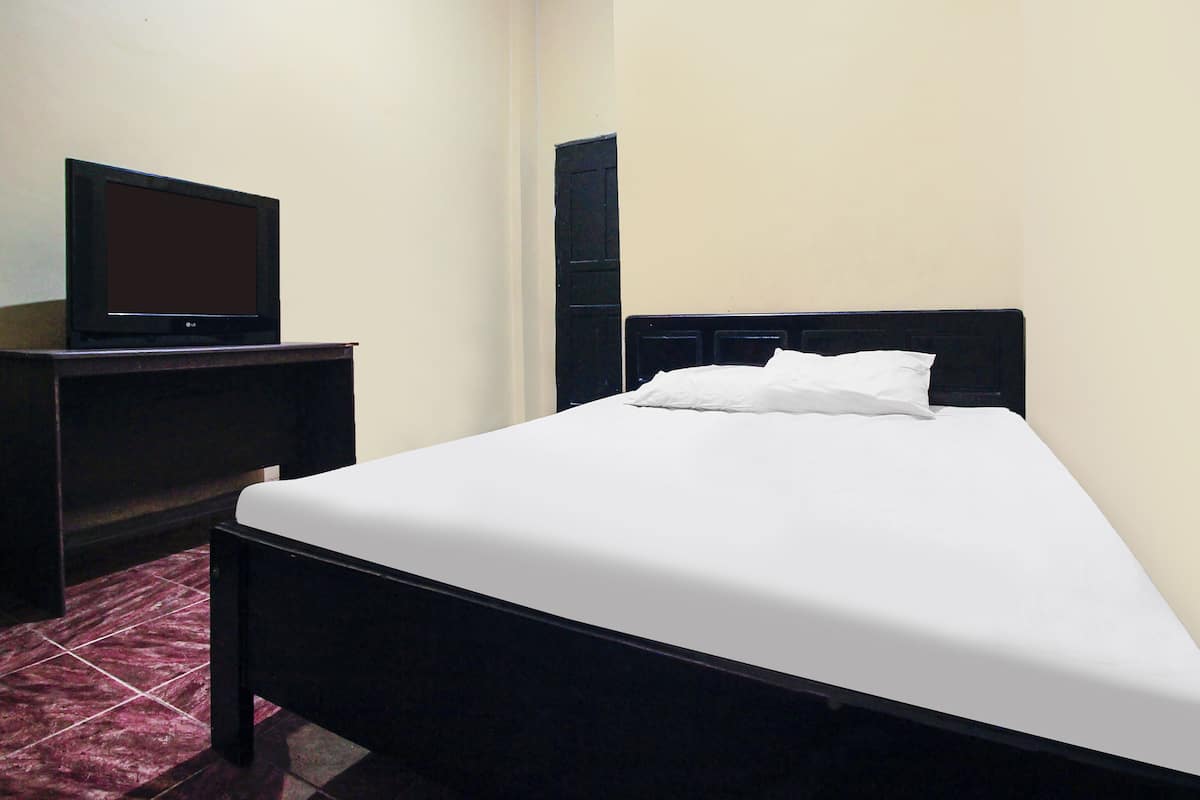 Una habitación con una cama, un televisor sobre un mueble bajo y un armario.
