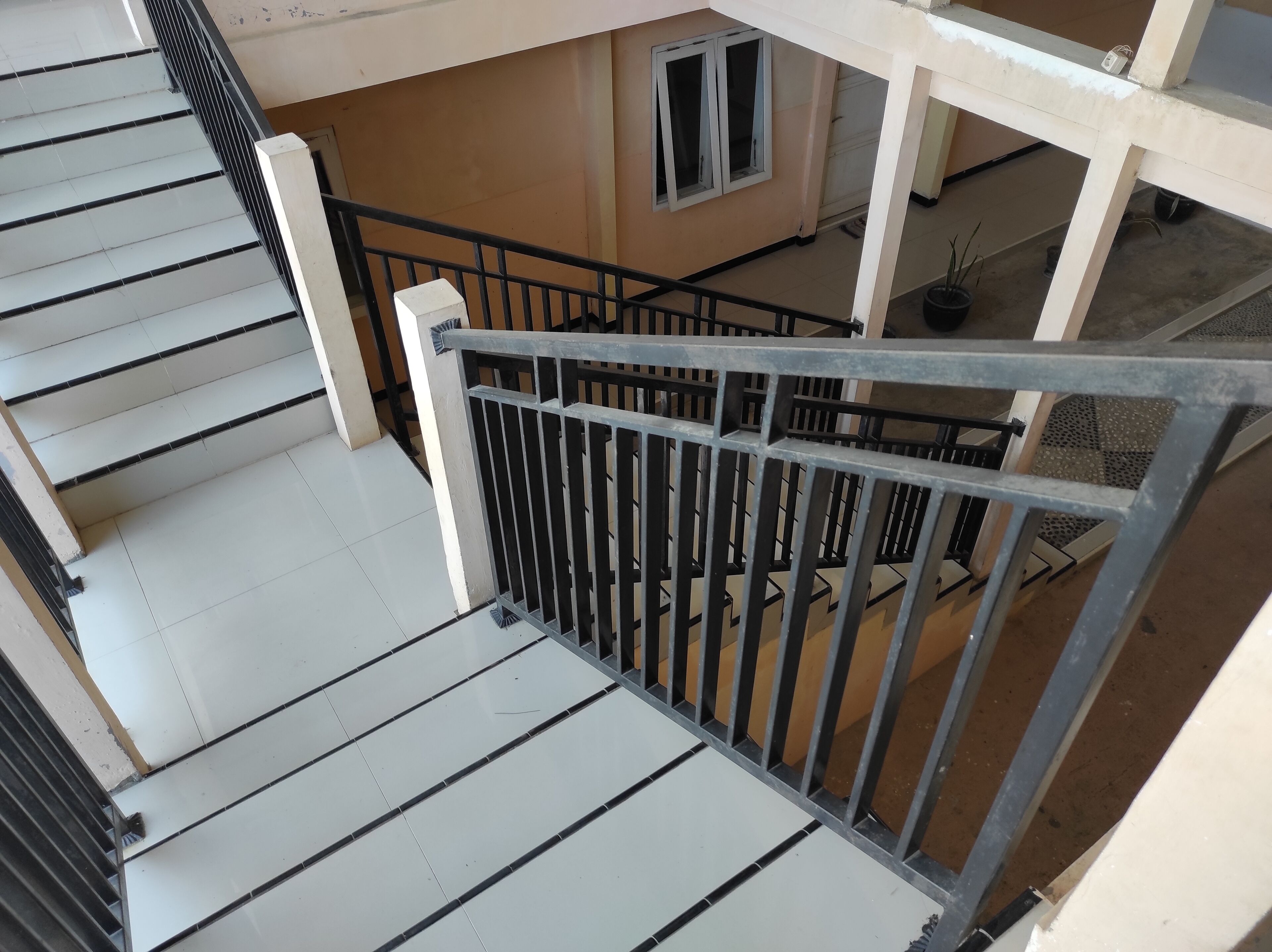Una escalera con barandilla de metal que baja a un nivel inferior.