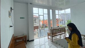Ein Zimmer mit einer Bank, einem kleinen Tisch und einem Balkon mit Geländer.