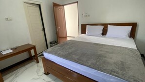 Ein Schlafzimmer mit einem hölzernen Bett, einem Nachttisch, einem Schreibtisch und einer Tür.