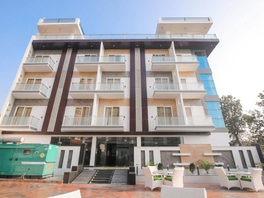 A multi-story hotel with balconies, a central entrance, and outdoor seating.