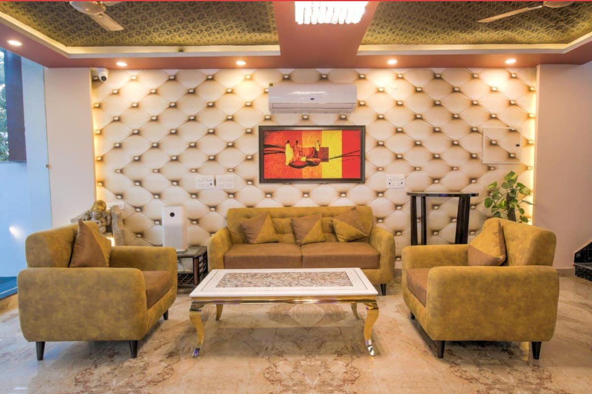Uma sala de estar com parede estofada, um sofá, duas poltronas, uma mesa de centro e um aparelho de ar condicionado.