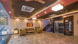 A lobby with a marble floor, a sofa set, a staircase, and a reception desk. - Amit House (Greater Noida)