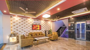 A lobby with a marble floor, a sofa set, a ceiling fan, and a staircase. - Amit House (Greater Noida)