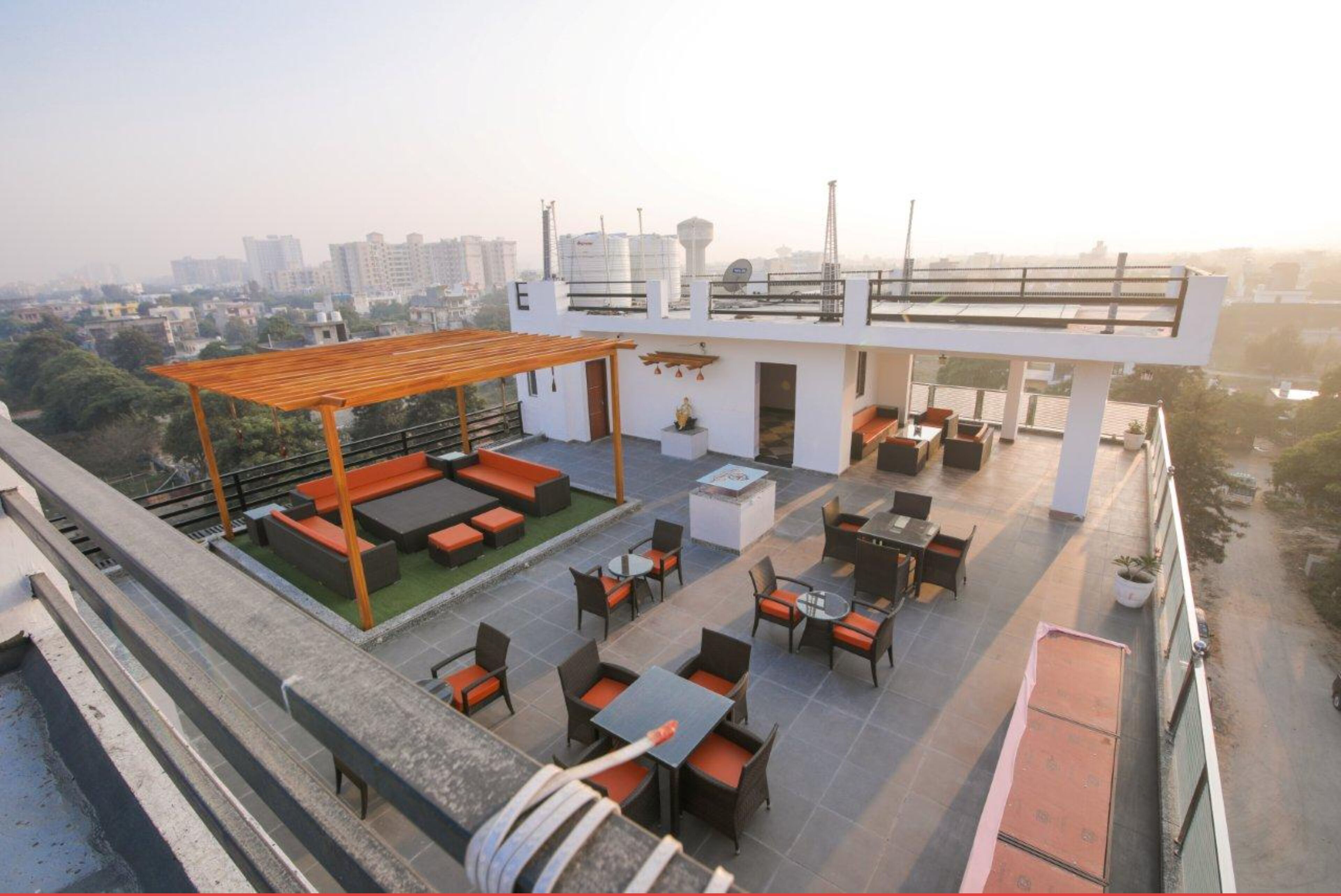 Una terraza en la azotea con mobiliario exterior, una pérgola y vistas a la ciudad.