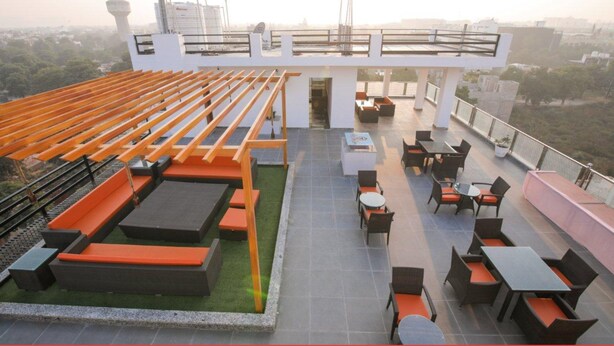 A rooftop terrace with seating areas, tables, and a view of the cityscape. - Amit House (Greater Noida)