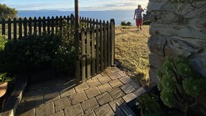 A stone wall with a wooden fence and a pathway leading to a beach. - Waterfront beach house overlooking one of Tassie's favourite surf breaks (Dodges Ferry)