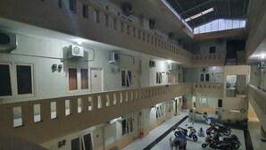Un immeuble à plusieurs niveaux doté de systèmes de climatisation, d’une cour intérieure aménagée avec des sièges et d’un escalier reliant les différents étages.