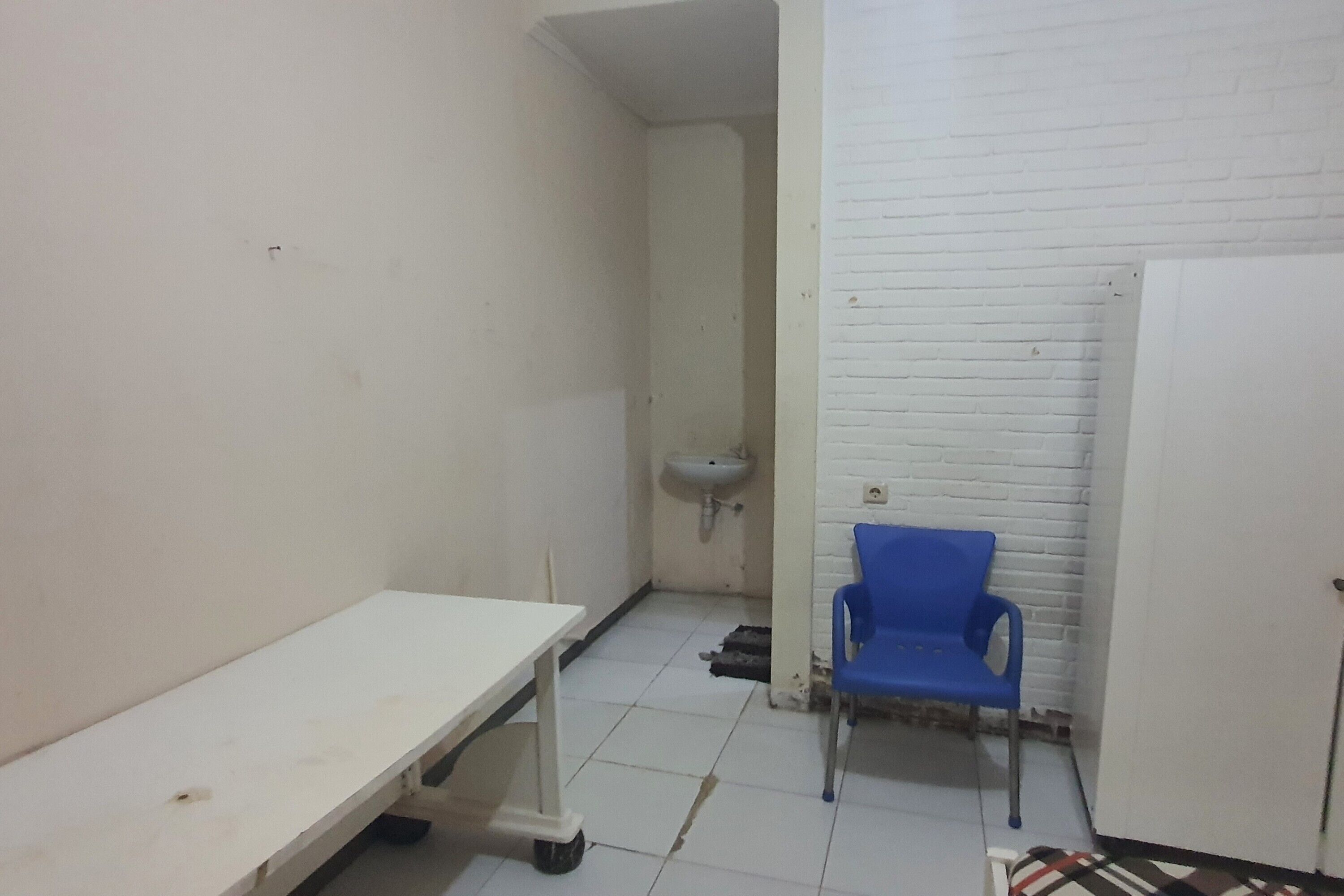 A small, clean room with a white sink, a blue chair, and a white table.