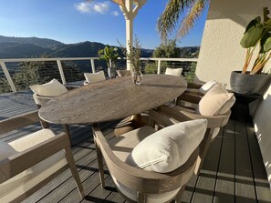 An outdoor patio with a round wooden table and cushioned chairs, surrounded by a white railing. - Cozy Retreat on The Santa Monica Mountains  (Topanga)
