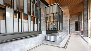 A modern lobby with a marble floor, a staircase with a glass railing, and a wooden ceiling. - OYO 93447 City Rooms Apartment (Tangerang)
