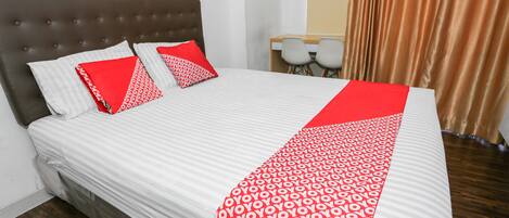 A neatly made bed with a patterned bedspread, two pillows, and a red accent.