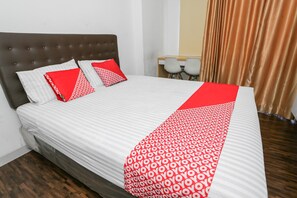 A neatly made bed with a patterned bedspread, two pillows, and a red accent. - OYO 93447 City Rooms Apartment (Tangerang)