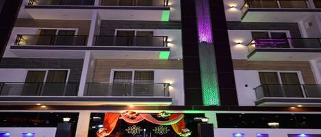 A multi-story hotel with balconies, a central staircase, and decorative lighting.