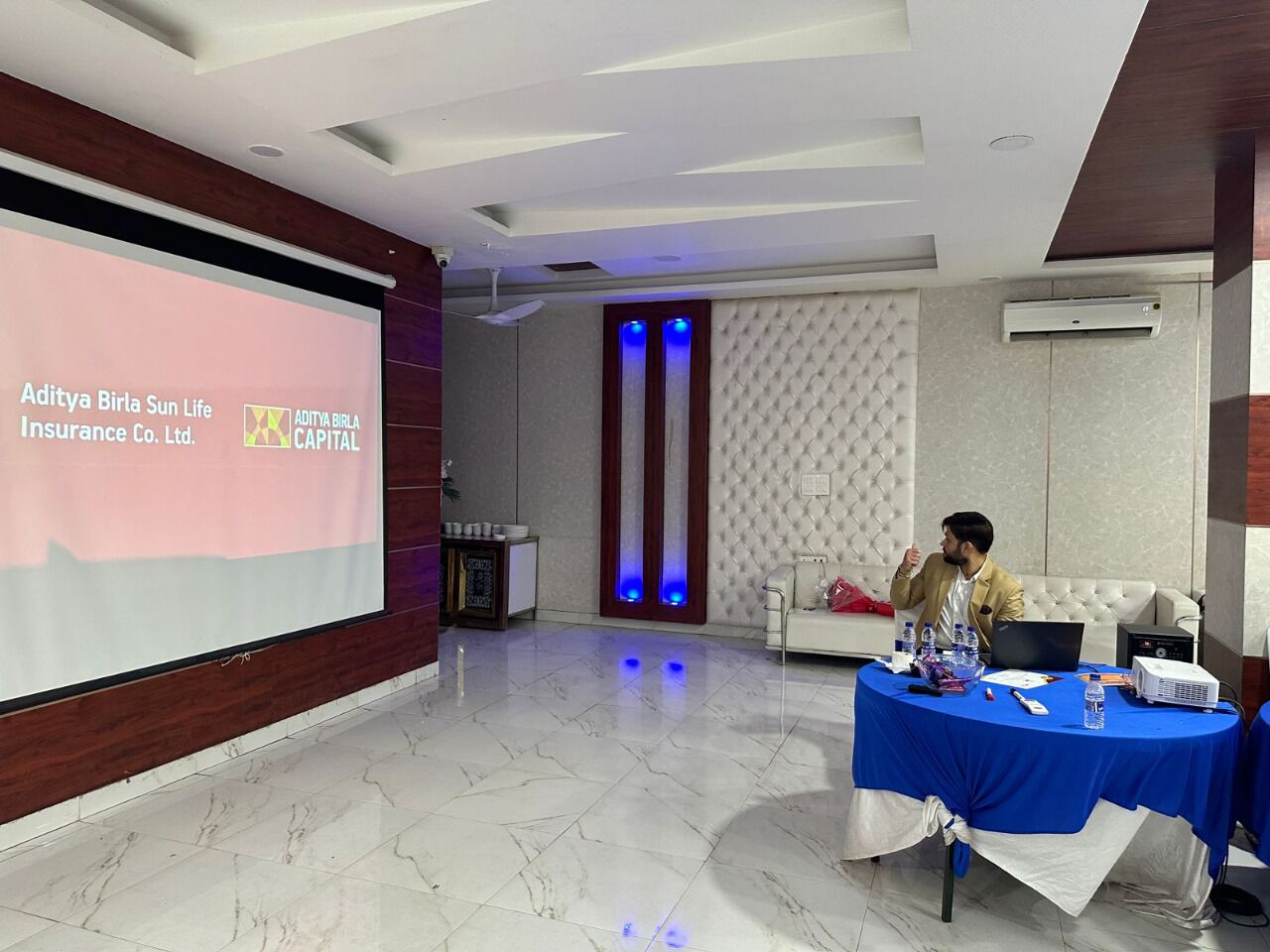 Une salle de conférence équipée d’un écran de présentation, d’une table avec un ordinateur portable et d’une personne assise.