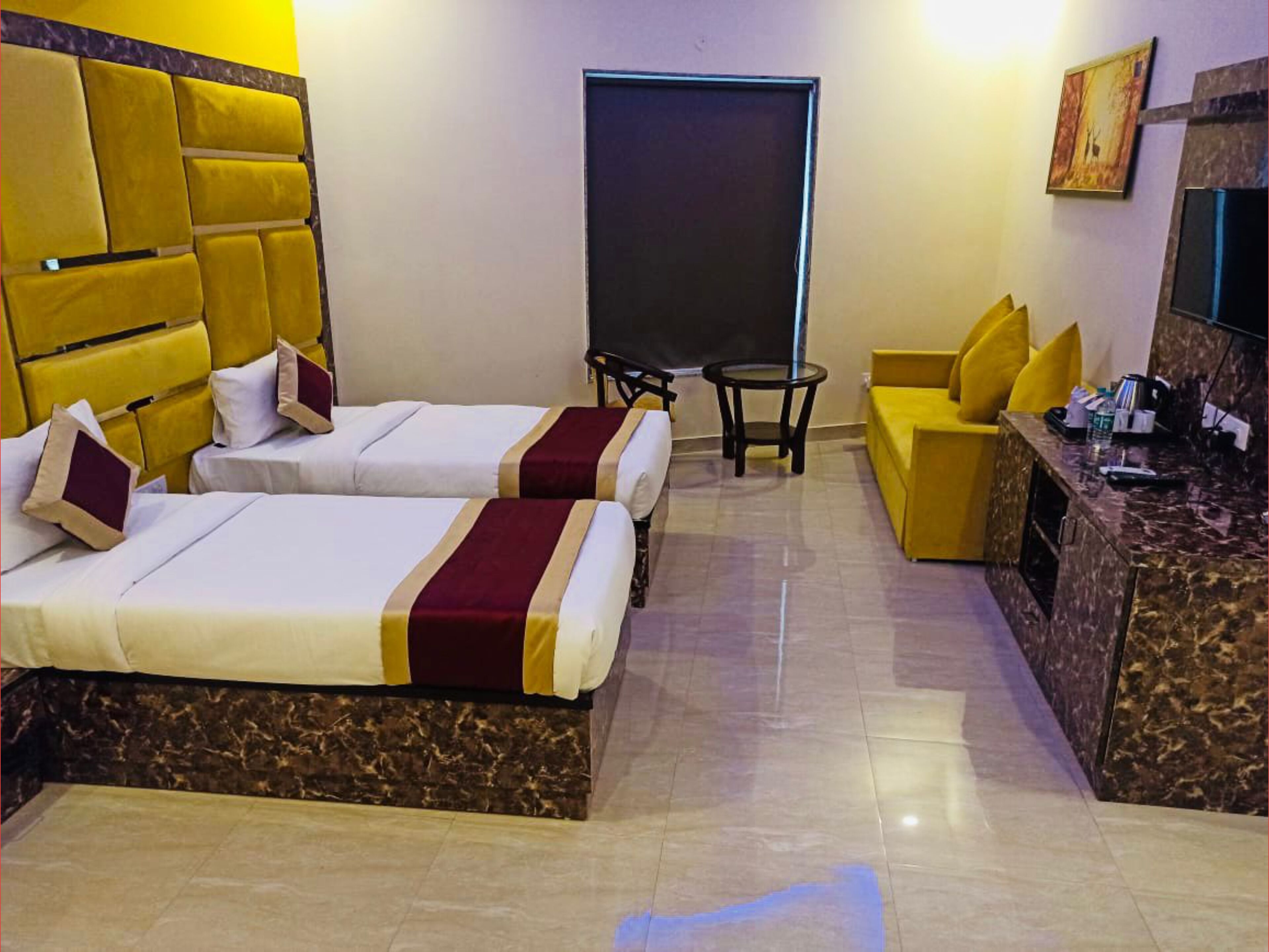 Habitación de hotel con dos camas, un sofá, un escritorio y una televisión.