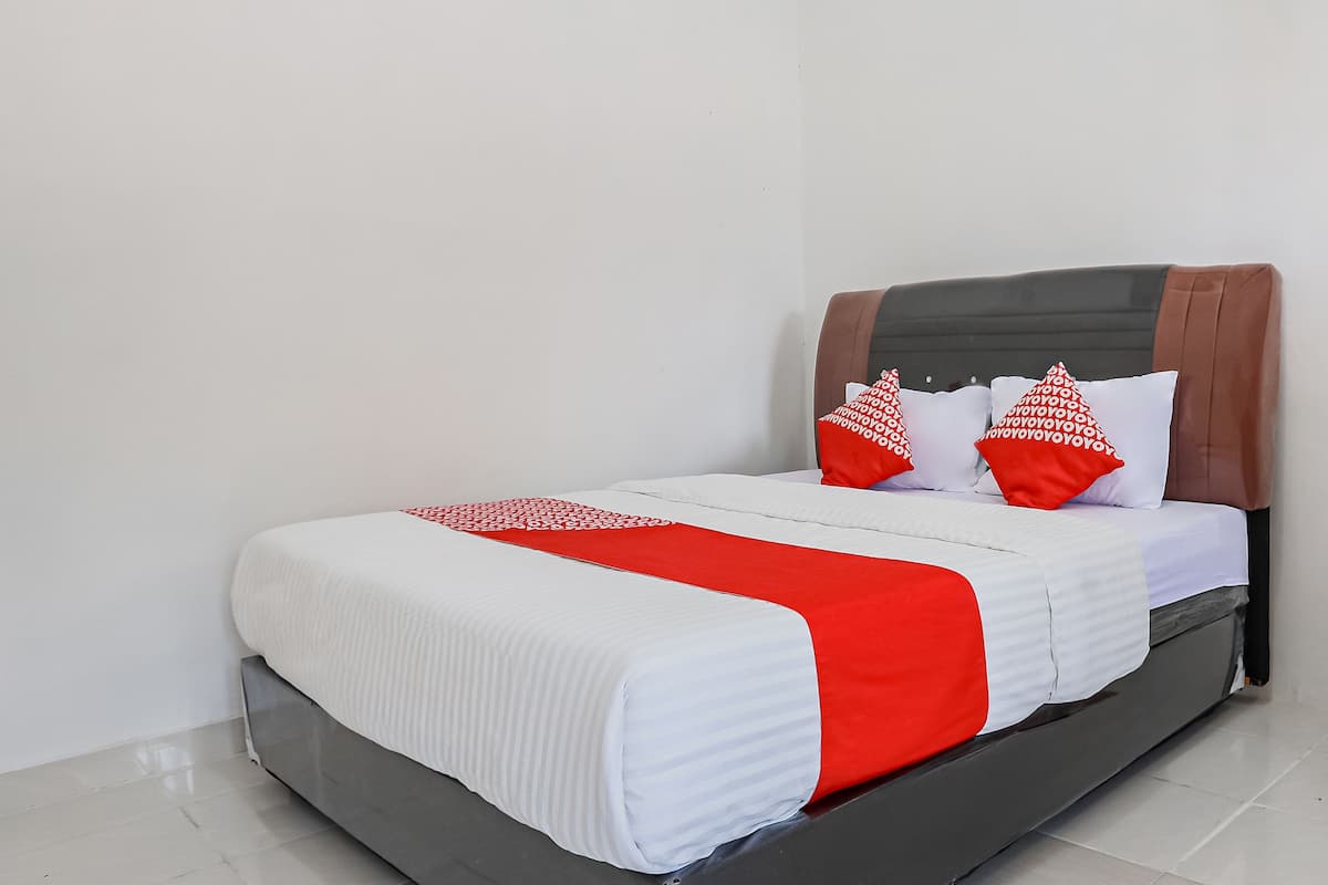 A bed with a white and red bedspread, two red pillows, and a brown headboard.