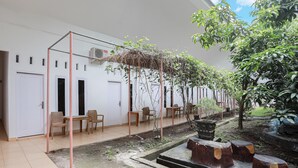 A courtyard with a pergola, seating area, and a small water feature. - Hotel O Wisma Silampari (Lubuklinggau)