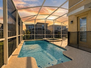 An indoor swimming pool with a glass ceiling, surrounded by a poolside area with a chair and a small table.