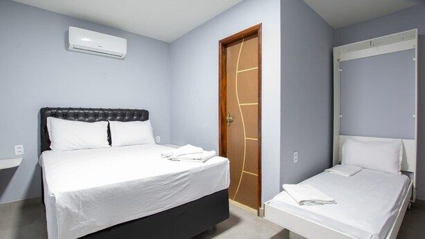 Une chambre à coucher comprenant un grand lit, un lit plus petit, une armoire et une porte au design original.