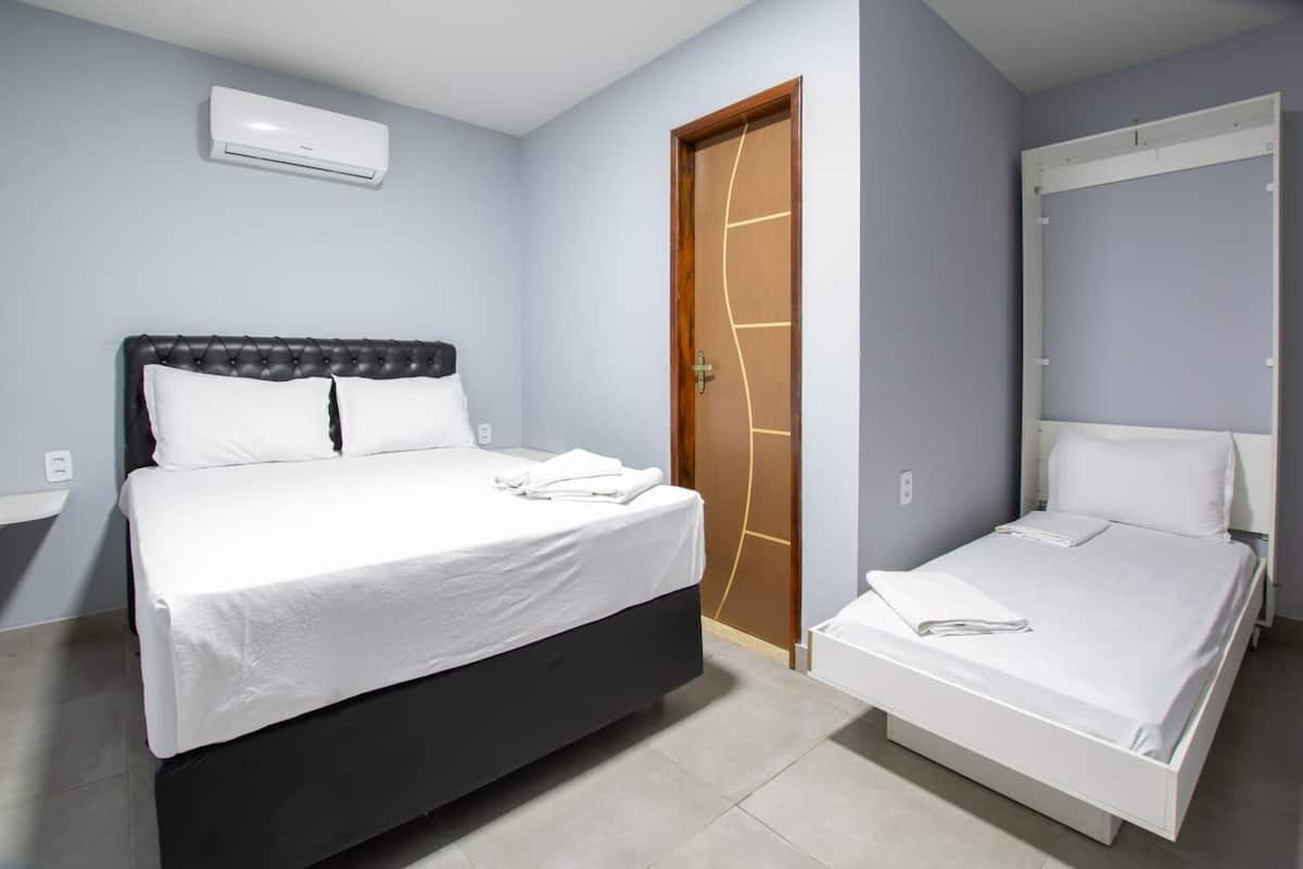 A bedroom with a large bed, a smaller bed, a wardrobe, and a door with a unique design.