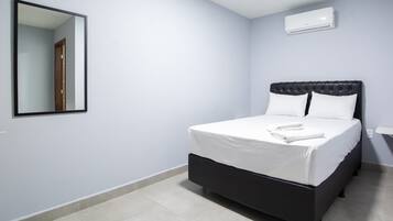 A bedroom with a bed, a mirror, and an air conditioning unit.