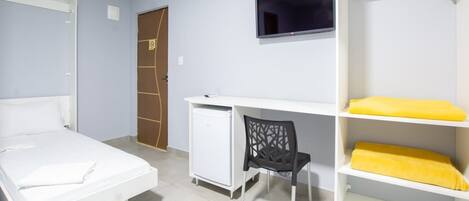 A room with a bed, a desk, a chair, and a wardrobe.