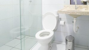 Une salle de bain moderne avec une douche à l’italienne en verre, des toilettes blanches et un lavabo en marbre.