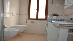 Ein Badezimmer mit Toilette, Bidet, Waschmaschine und Waschbecken.