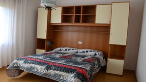 Ein Schlafzimmer mit Bett, einem Kleiderschrank mit vielen Fächern und einer Lampe.