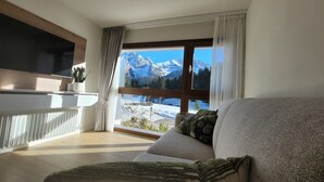 A modern living room with a large window offering a mountain view.