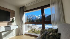 A modern living room with a large window offering a mountain view.