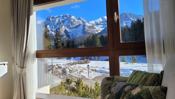 A room with a large window offering a mountain view.