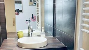 Een badkamer met een witte wastafel, een spiegel en een wit kastje met lades.