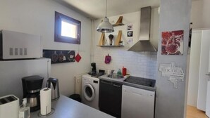 Een compacte keuken met een wasmachine, vaatwasser en een magnetron.