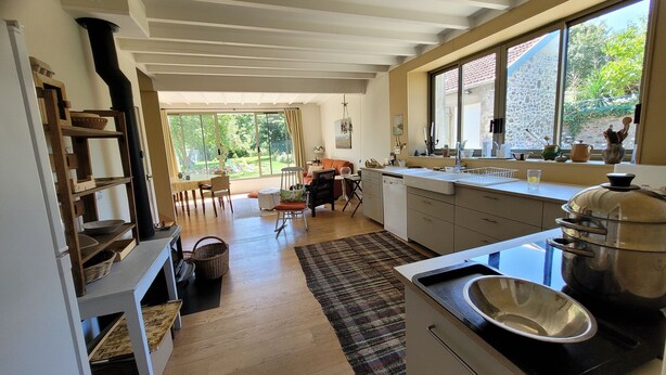 Una cocina moderna con un ventanal grande, suelo de madera y un comedor con mesa y sillas.