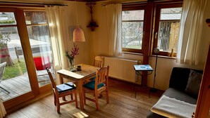 A cozy room with a wooden floor, a dining table with chairs, a sofa, and a small side table. - Gemütliche, Modern Ausgestattete Ferienwohnung mit Sonnenterasse und Bergblick (Oberammergau)