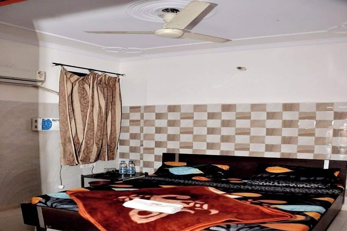 A bedroom with a bed, a ceiling fan, a window with curtains, and a tiled wall.