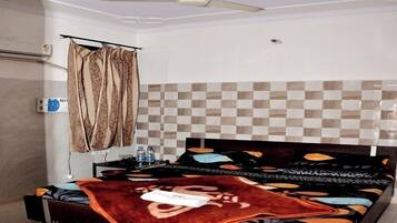 A bedroom with a bed, a ceiling fan, a window with curtains, and a tiled wall.
