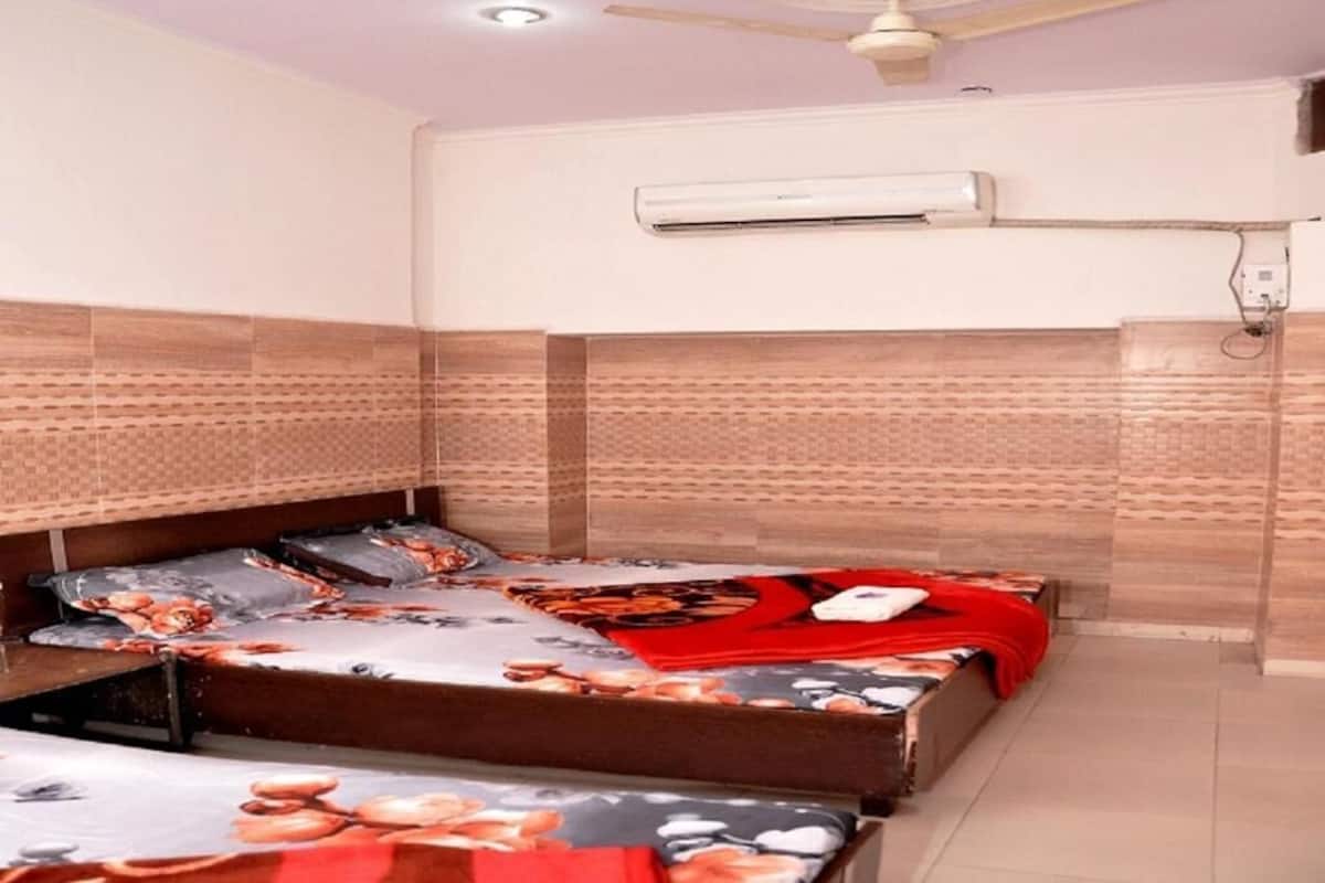 A bedroom with two beds, an air conditioning unit, and a ceiling fan.