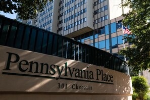 Señal de Pennsylvania Place en el número 301 de Chestnut, que muestra un edificio moderno con ventanas de vidrio reflectante y una bandera estadounidense.
