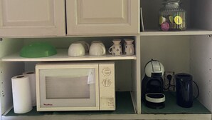 Eine Küche mit weißen Schränken, einer Mikrowelle, einer Kaffeemaschine und einem Einmachglas.