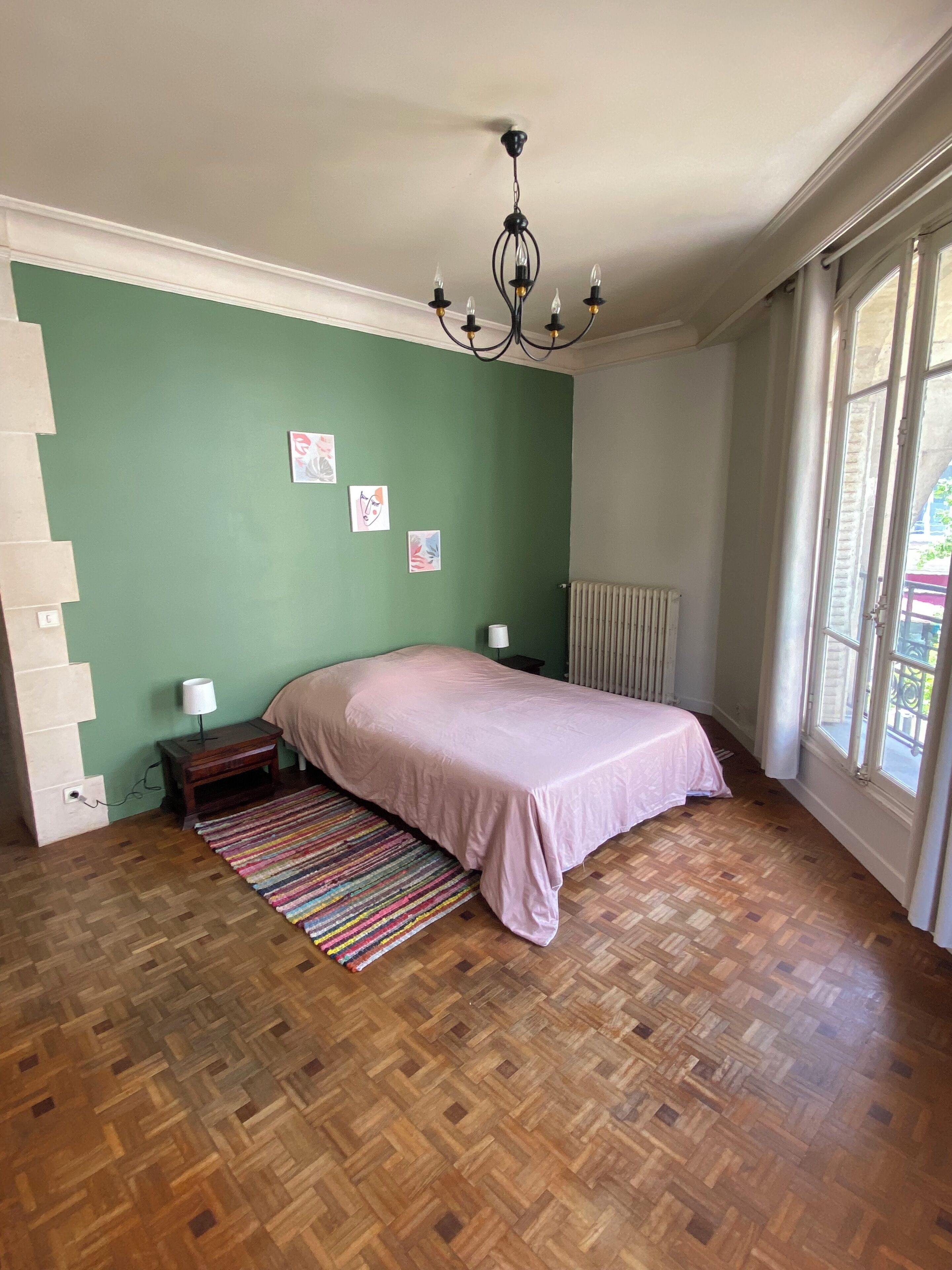 Una camera da letto con un letto, un comodino, un termosifone e una finestra con tende.
