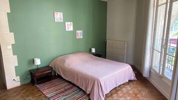 Una camera da letto con un letto, un comodino, un termosifone e una finestra con tende.