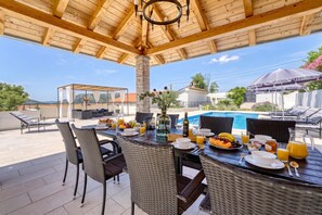 An outdoor dining area with wicker furniture, a pool, and a covered patio. - Pool House Edita (Bribir)