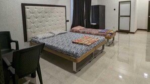 A spacious bedroom with two beds, a desk, and a chair. - Havelock Inn Resort (Mumbai)