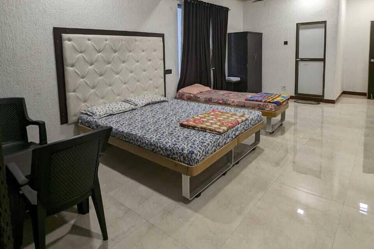 A spacious bedroom with two beds, a desk, and a chair.