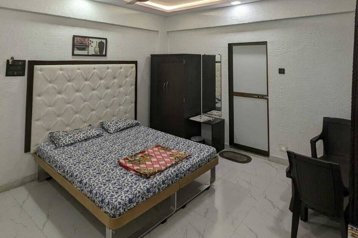 A bedroom with a bed, a wardrobe, a desk, a chair, and a ceiling fan.