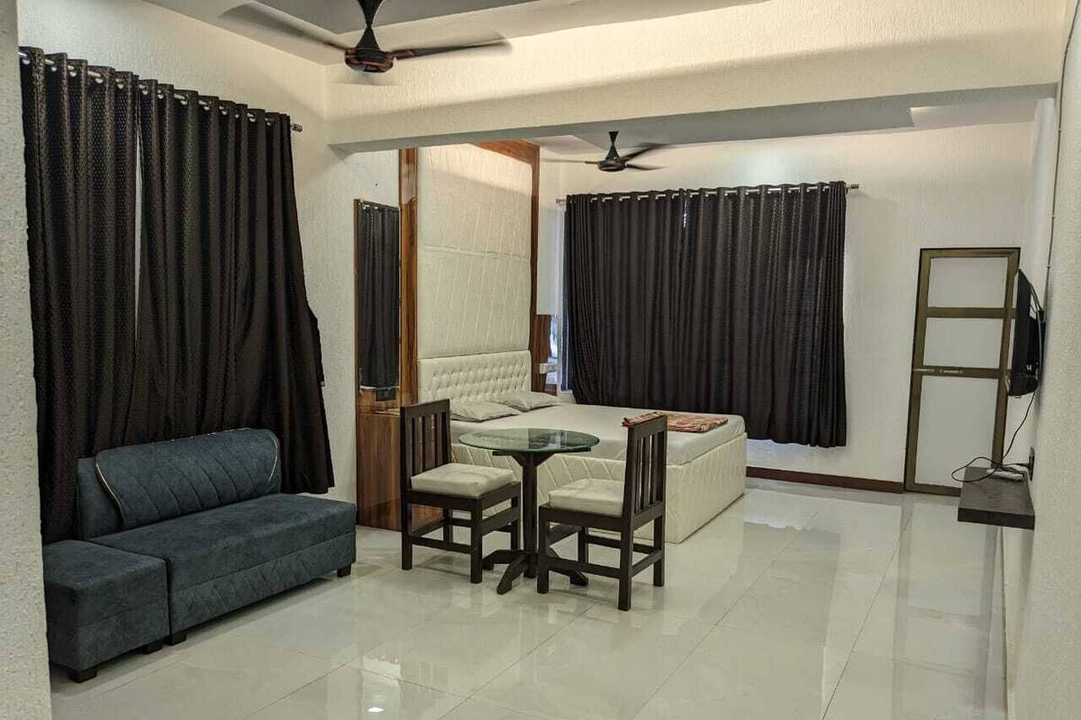 A living room with a sofa, a table with chairs, a TV, and a ceiling fan.
